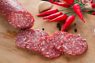 Smoked sausage sliced into pieces, slices of garlic and red chili peppers on a dark background. Not a healthy diet. The concept of cooking.