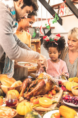 Thanksgiving Celebration Tradition Family Dinner Concept.family having holiday dinner and cutting turkey.Young black adult woman and her daughter happy.