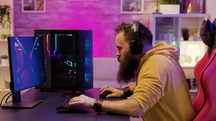 Professional game player wearing headphones in a room with colorful neons © DC Studio