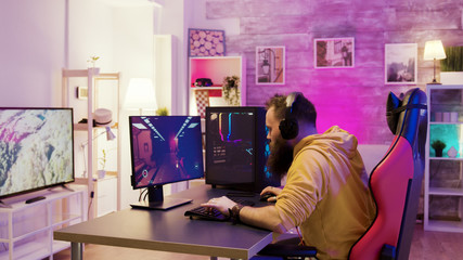 Successful man playing online video games in a room with colorful neons