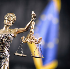 Scales of Justice, Justitia, Lady Justice in front of the European Union flag in the background.