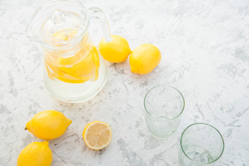 Homemade lemonade on a light background concept. Lemons, glasses, mint, jug and copy space. Summer refreshing drink lemonade.