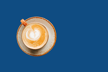 Coffee with milk in a cup. Cappuccino. On a blue background isolated. Top view. Free copy space.