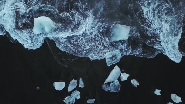 Top view from drone, Wave crash on black beach with pieces of ice, Iceland