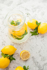 Fototapeta na wymiar Homemade lemonade on a light background concept. Lemons, glasses, mint, jug and copy space. Summer refreshing drink lemonade.