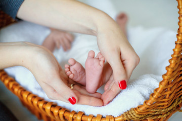 loving mom holds the legs of a newborn in her arms