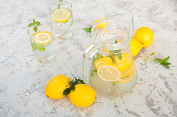 Homemade lemonade on a light background concept. Lemons, glasses, mint, jug and copy space. Summer refreshing drink lemonade.