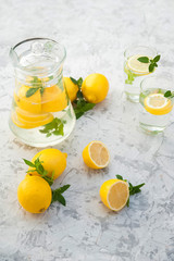 Homemade lemonade on a light background concept. Lemons, glasses, mint, jug and copy space. Summer refreshing drink lemonade.