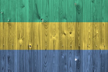 Gabon flag depicted in bright paint colors on old wooden wall. Textured banner on rough background