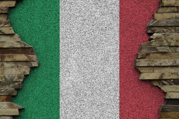 Italy flag depicted in paint colors on old stone wall closeup. Textured banner on rock wall...