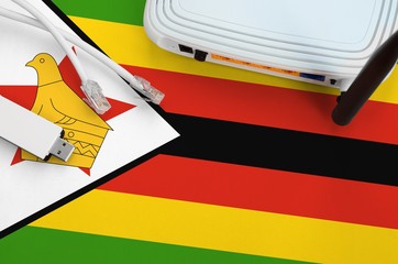Zimbabwe flag depicted on table with internet rj45 cable, wireless usb wifi adapter and router....