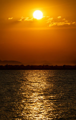 Sun, clouds, lake malawi and coastline with orange sky
