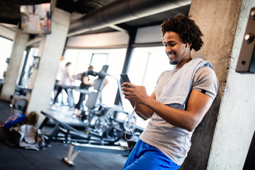 Fototapeta na wymiar Young muscular man using mobile phone at the gym in exercise break