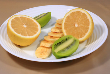 On the plate are pieces of orange, kiwi and banana