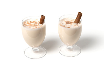 Eggnog Christmas cocktail in a transparent wine glass, decorated with cinnamon stick, sprinkled with grated nutmeg. Isolated on white background. Copy space.