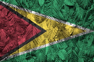Guyana flag depicted on many leafs of monstera palm trees. Trendy fashionable backdrop