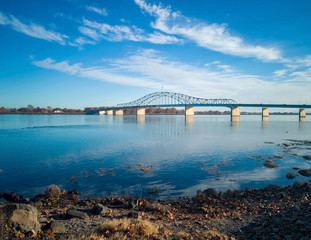 Historic blue and white arch truss bridge over the Columbia River with blue skies and clouds on a sunny morning in Kennewick-Pasco Washington