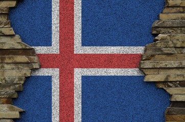 Iceland flag depicted in paint colors on old stone wall closeup. Textured banner on rock wall...
