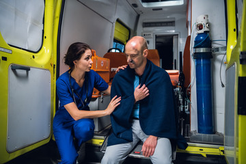 Fototapeta na wymiar Ambulance car, nurse talks with a man in blanket