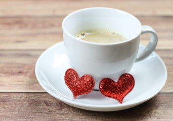 Two red glitter heart  with on coffee cup saucer ,selective focus.