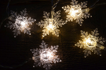 Snowflakes garland lights on old wooden rustic background.Winter holidays,Merry Christmas, Happy New Year concept.Soft focus.