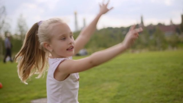 Two adorable long-hair sisters in blue and rose dresses dancing on the meadow