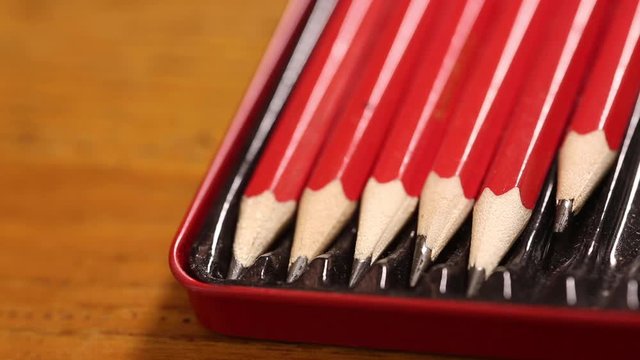 Close up of artists drawing pencils in a tin. A man's hand takes a pencil from the tin and replaces it.