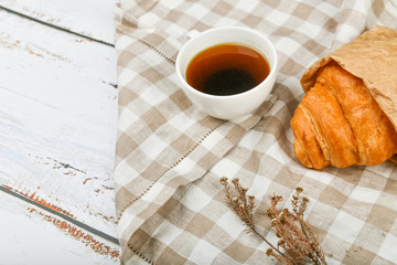 coffee with a croissant. the beginning of the morning. A cup of coffee. fresh french croissant. Coffee cup and fresh baked croissants on a wooden background. View from above.