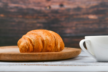 croissant and a cup of coffee on the table. Fresh french croissant. on a wooden background. View from above. Morning breakfast with a croissant. French breakfast Excellent homemade. Fresh tower.