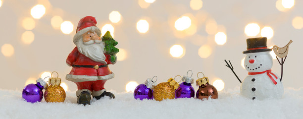 banner with many different christmas items on white snow with many small, shining lights in the background