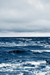 Classic blue sea beach. North sea. Stormy weather: strong waves, gloomy sky, sea foam. Classic blue color sea. A place for your writing. Copy space