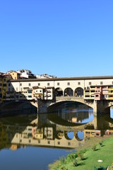 Naklejka premium Ponte Vecchio and Arno River with blue sky and water reflection. Florence, Italy.