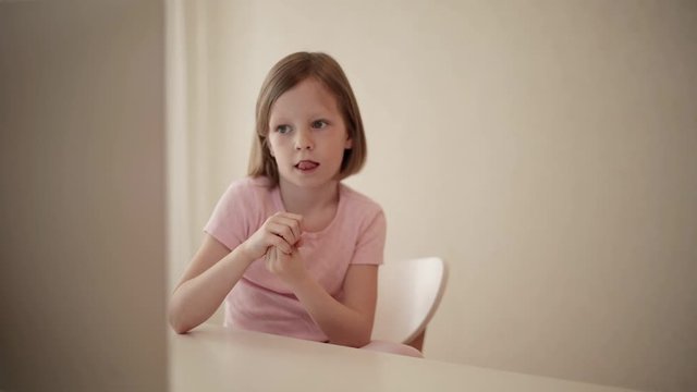 Little funny girl (8 years old) is watching a video on a computer.