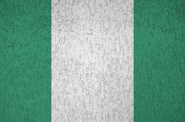 Nigeria flag depicted in bright paint colors on old relief plastering wall. Textured banner on...