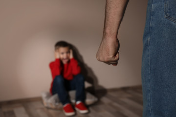Man threatening his son indoors, closeup. Domestic violence concept