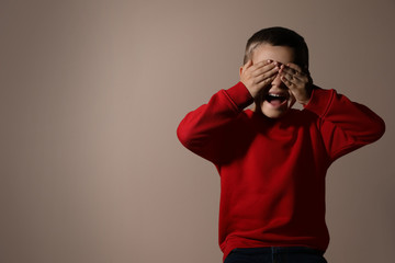 Scared little boy on beige background, space for text. Domestic violence concept