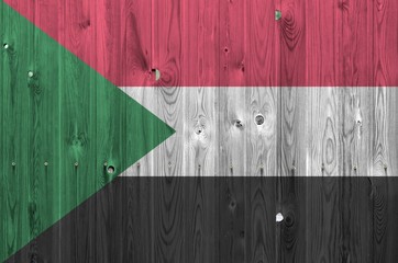 Sudan flag depicted in bright paint colors on old wooden wall. Textured banner on rough background