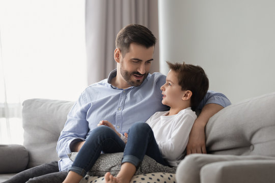 Little son having confidence conversation with father at home