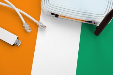 Ivory Coast flag depicted on table with internet rj45 cable, wireless usb wifi adapter and router....