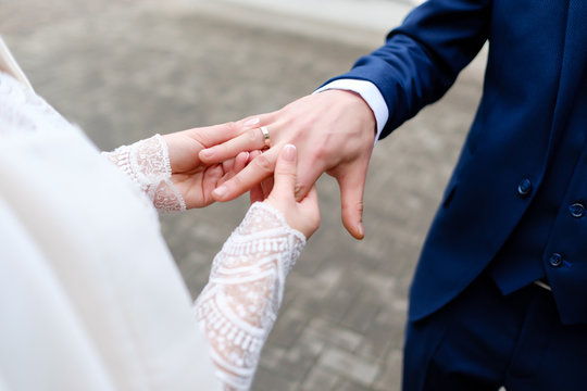 Wedding details  - bride put wedding gold ring to groom. Closeup photo