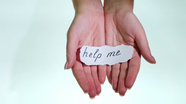 Female hands show an inscription on a piece of paper - Help me