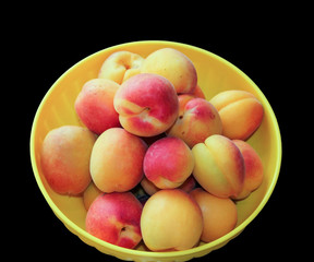 Ripe apricots in a bowl isolated on black