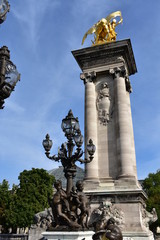 Fototapeta na wymiar Pont Alexandre III detail, column with gilded sculpture and bronze street light. Paris, France.