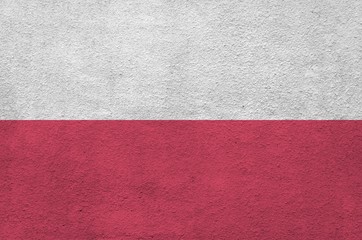 Poland flag depicted in bright paint colors on old relief plastering wall. Textured banner on rough...