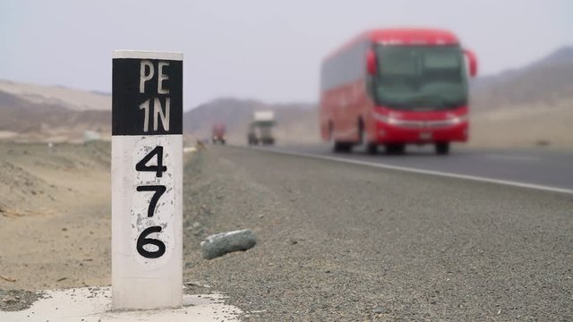Panamericana road (Peru) with a pylon with the highway number PE1N and a bus in the background, South America. PERU