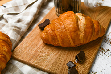 french chocolate croissants top view. the beginning of the morning. Fresh french croissant. Coffee cup and fresh baked croissants on a wooden background. View from above.