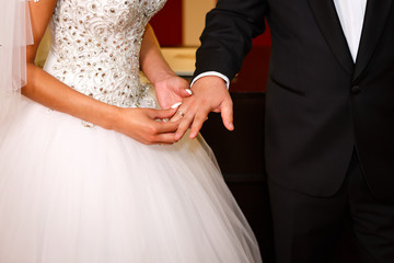 Newlyweds exchanging wedding rings, bride putting the ring on the groom. Concept photo of atelier for making wedding dresses and wedding magazine cover