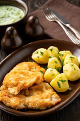 Chop pork cutlets , served with boiled potatoes and tzatziki dip. 