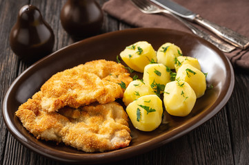 Chop pork cutlets , served with boiled potatoes and tzatziki dip. 