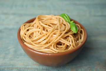 Tasty buckwheat noodles in bowl on blue wooden table